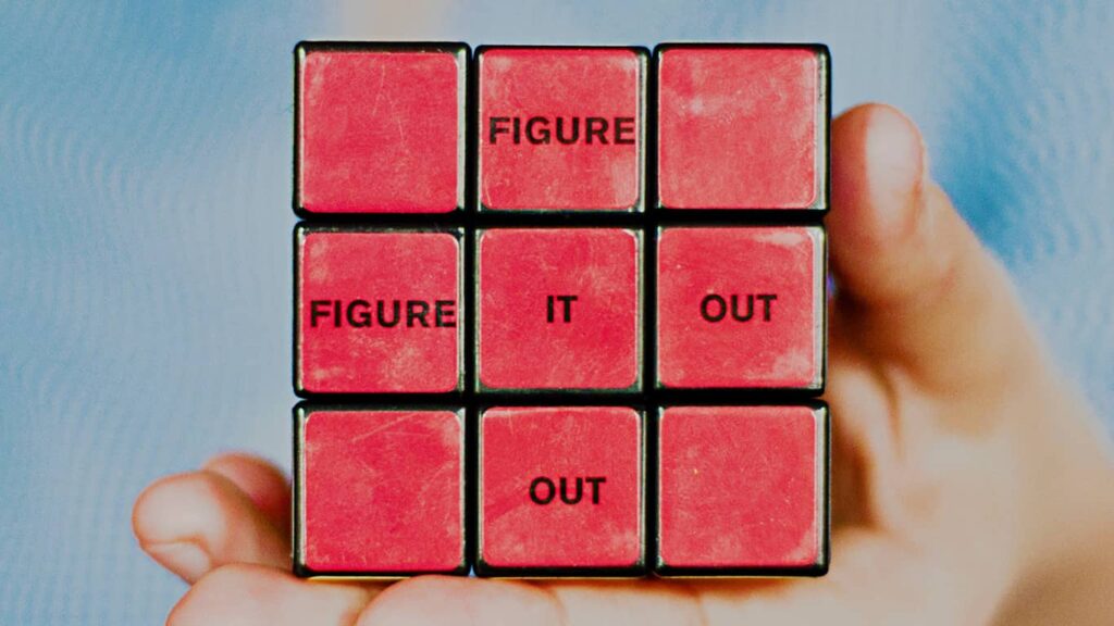 Face de um cubo mágico com as palavras "figure it out", ou "resolva isso", em português, fazendo referência à competência de resolução de problemas na Engenharia de Dados.