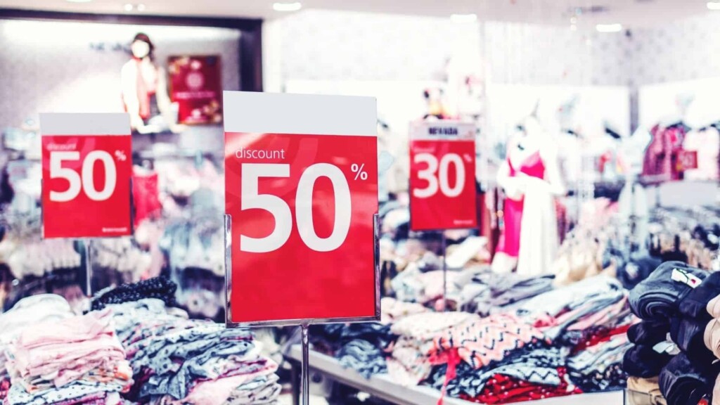 Loja de roupas, com diversos tipos de roupas à mostra e placas indicando desconto de 30% e 50% em vários produtos.