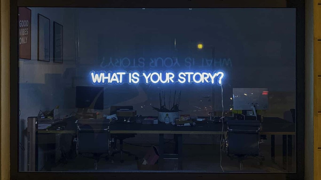 Janela com letreiro em led azul escrito “What is your story?”, incentivando os leitores a compartilharem experiências com o Blog MBA USP/Esalq. 