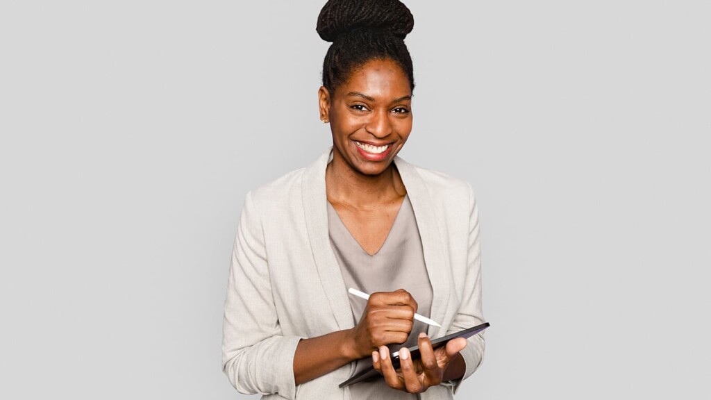 mulher sorrindo e segurando um tablet onde estudava as tendências da transformação digital.
