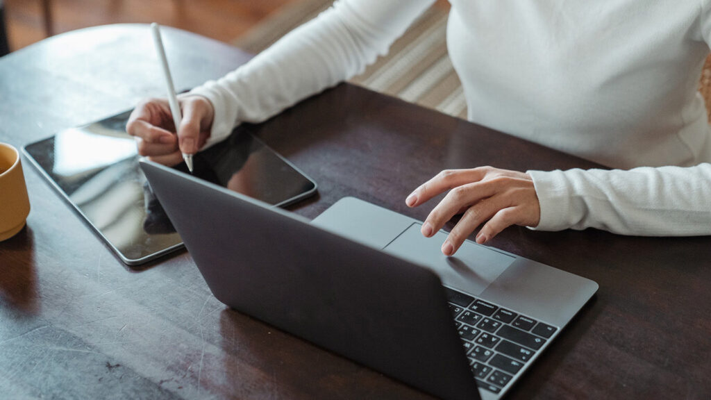 Imagem de uma pessoa usando o computador enquanto faz anotações em alusão à sua organização para a gestão de e-commerce