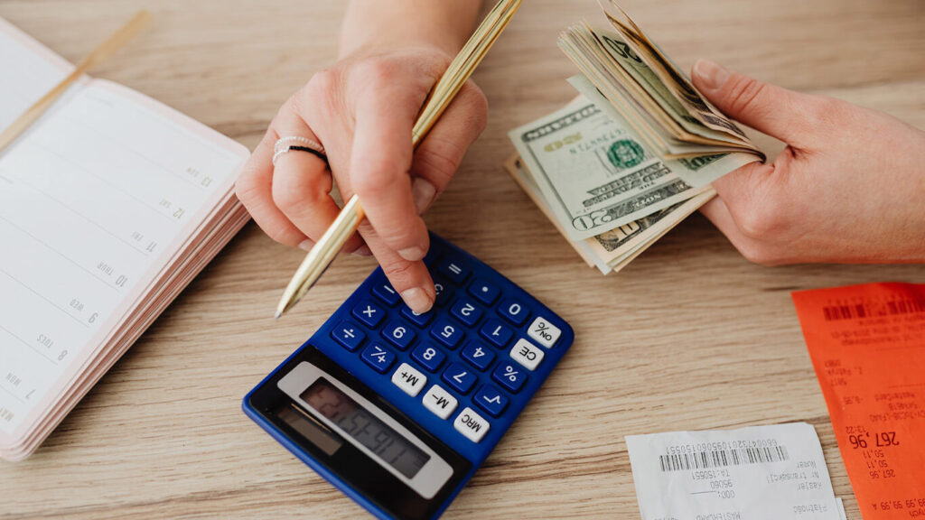 imagem de uma calculadora e de notas fiscais para simbolizar os cálculos financeiros de pequenos negócios devido aos impactos da inflação
