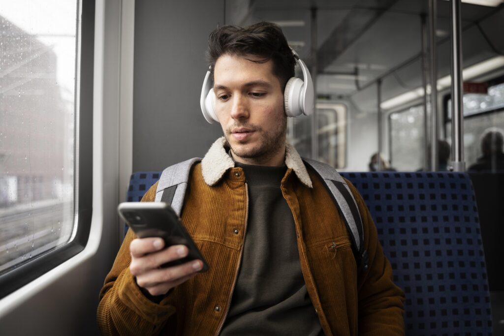 Pessoa no ônibus, com o celular na mão e fone de ouvido, mostrando a flexibilidade do MBA EAD