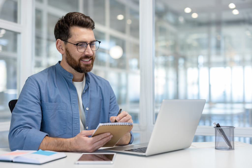 Homem sorridente em escritório, participando de Executive MBA.