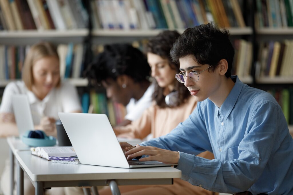 Jovens em biblioteca pesquisando se é possível fazer MBA antes de terminar a graduação.