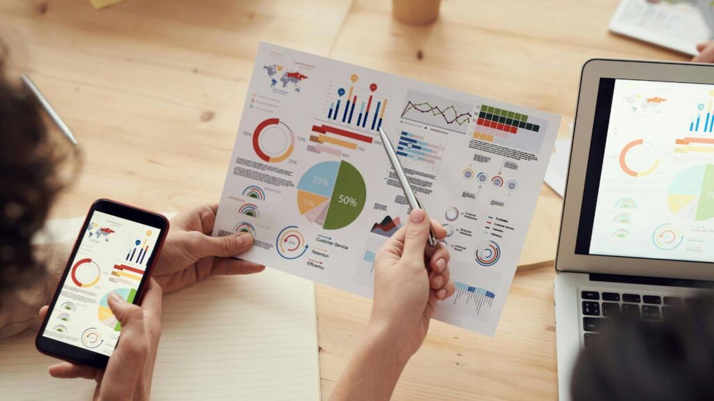 Pessoas analisando gráficos e dados, representando a aplicação de estratégias de marketing digital no MBA em Marketing.